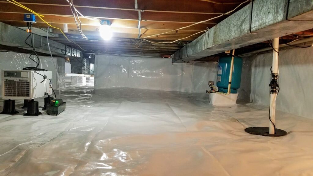 A clean, encapsulated crawl space with white vapor barrier sheets covering the floor and walls, exposed pipes, wiring, and a dehumidifier are visible.