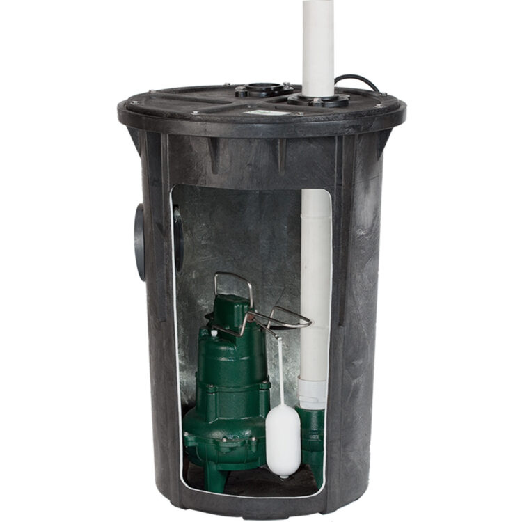 A black sump basin with a green sump pump, white float switch, and vertical discharge pipe inside.